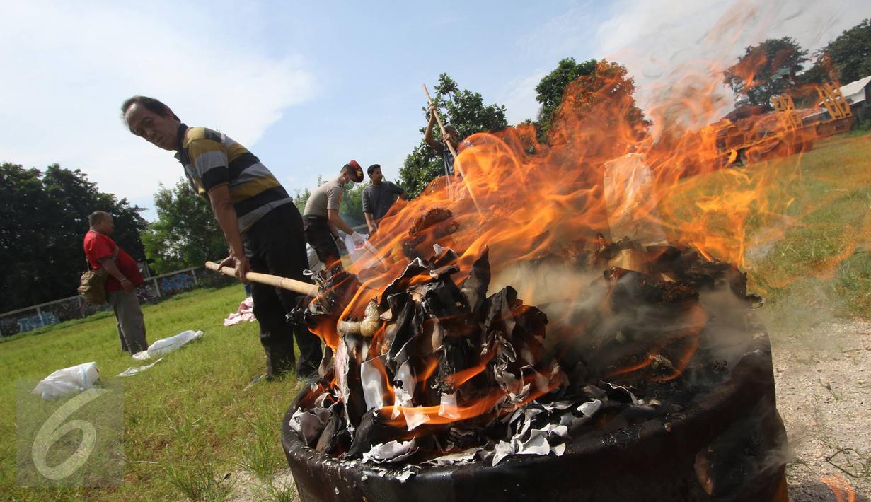 Petugas memusnahkan barang bukti narkotika dan miras ilegal di halaman Polsek Metro Palmerah, Jakarta, Rabu (22/6). 10.150 botol miras, 3.597 gram shabu, dan 104 butir pil ekstasi dimusnahkan petugas. (Liputan6.com/Immanuel Antonius)