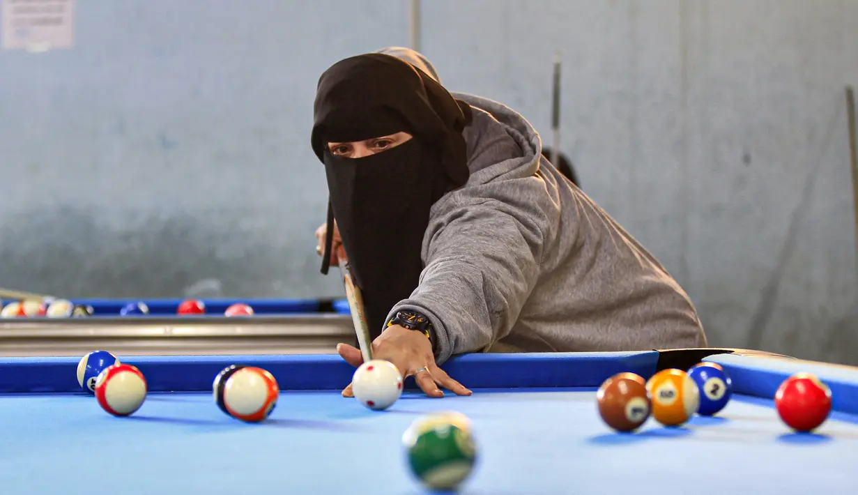 Seorang wanita membidik bola saat mengikuti kejuaraan biliar lokal di sebuah gedung olahraga di ibu kota  Sanaa, Yaman  (16/12/2019).  (AFP/Mohammed Huwais)
