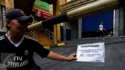 Warga memegang kertas pemberitahuan yang terpasang di pusat perbelanjaan Blok B Tanah Abang, Jakarta, Jumat (24/7/2015). Pusat grosir terbesar di Asia ini masih terlihat tutup dan baru akan buka kembali pada 27 Juli mendatang. (Liputan6.com.Johan Tallo)