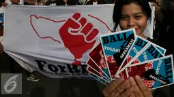 Salah satu peserta memperlihatkan brosur saat aksi di Bundaran Hotel Indonesia, Jakarta, Minggu (4/9). Mereka menyerukan Tolak Reklamasi Teluk Benoa. (Liputan6.com/Johan Tallo)