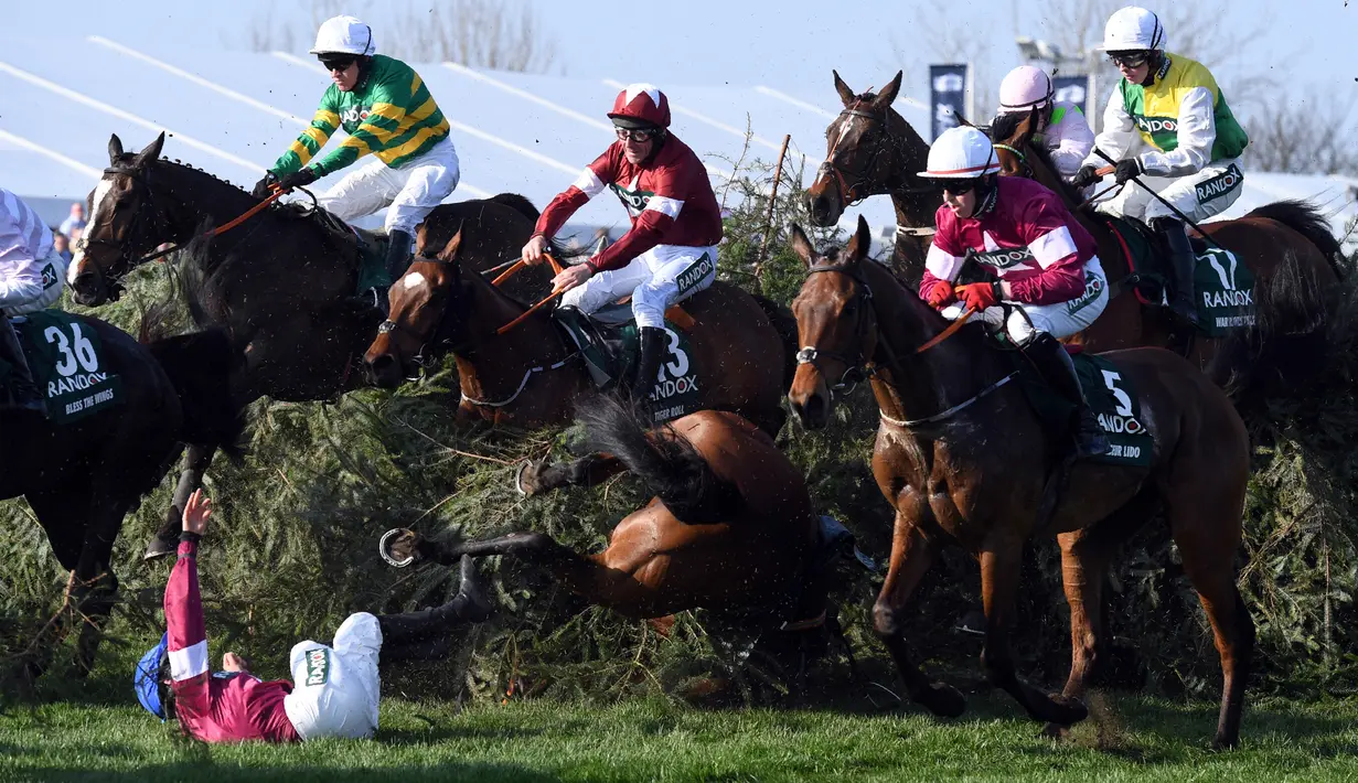 Seorang joki bernama Rachael Blackmore terguling ditanah saat mengikuti pacuan kuda Grand National di Aintree Racecourse di Liverpool, Inggris (14/4). Akibat insiden itu, Rachael Blackmore tidak dapat melanjutkan balapannya. (AFP/Paul Ellis)
