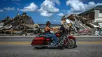 Seorang pengendara sepeda motor melewati puing-puing yang menumpuk dari rumah yang hancur setelah melewati Badai Ian di Pulau Matlacha di Lee County, Florida pada 7 November 2022. Pantai timur Florida berada di bawah pengawasan badai saat negara bagian itu bergulat dengan kehancuran Badai Ian. (AFP/ Giorgio Viera)