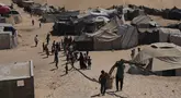 Pengungsi Palestina berjalan melalui kamp tenda di Muwasi, kawasan yang telah ditetapkan Israel sebagai zona aman, di Khan Younis, bagian selatan Jalur Gaza, Minggu 21 September 2025. (AP Photo/Jehad Alshrafi)