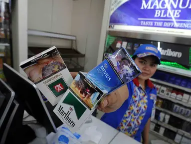Seorang karyawati menunjukan kemasan rokok yang telah berganti peringatan bergambar di minimarket, Jakarta, Selasa (24/6/14). (Liputan6.com/Johan Tallo)