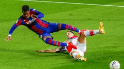Pemain Barcelona, Junior Firpo, terjatuh saat berebut bola dengan pemain Alaves, Edgar Mendez, pada laga Liga Spanyol di Stadion Camp Nou, Sabtu (14/2/2021). Barcelona menang dengan skor 5-1. (AP Photo/Joan Monfort)