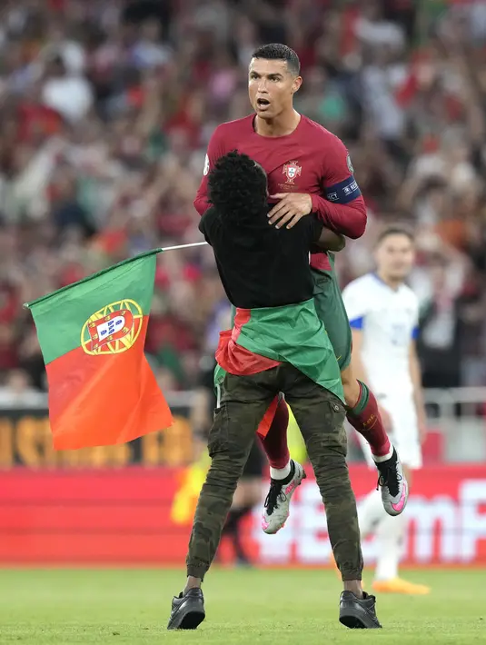 Fans yang memakai baju serba hitam itu kemudian memeluk Cristiano Ronaldo. Dia juga bersimpuh di hadapan bomber 38 tahun tersebut. (AP Photo/Armando Franca)