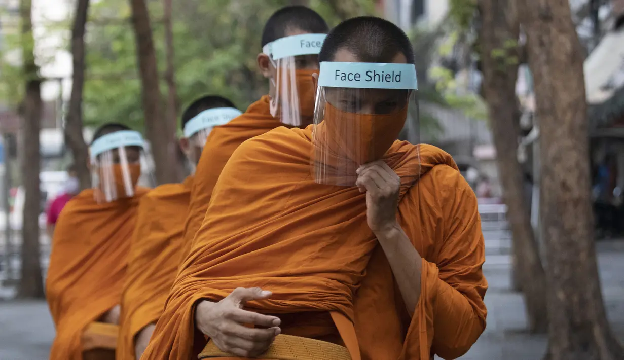 Para biksu Buddha memakai pelindung wajah untuk melindungi diri dari virus corona COVID-19 saat mengumpulkan sedekah di Bangkok, Thailand, Selasa (31/3/2020). Hingga 30 Maret 2020 sore, jumlah kasus COVID-19 di Thailand sebanyak 1.524 positif, 229 sembuh, dan 9 meninggal. (AP Photo/Sakchai Lalit)