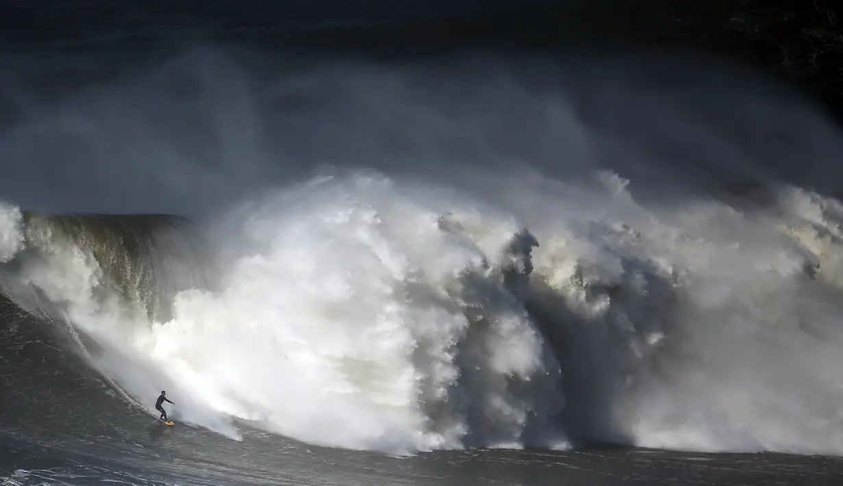 Seorang peselancar bermain diatas ombak yang besar di Praia do Norte, Nazare, Portugal, (19/2/16). Pantai ini memiliki kedalaman 5.000 meter dan membentang sekitar 230 kilometer. (REUTERS/Rafael Marchante)