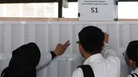 Peserta tes seleksi CPNS Kemenkumham mengecek no pendaftaran di gedung BKN, Jakarta, Senin (11/9). Pada 2017, tercatat 1.116.138 pelamar CPNS mendaftar di lingkungan Kemenkumham. (Liputan6.com/Helmi Fithriansyah)