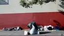 Seseorang berlutut di trotoar saat tunawisma tidur di komunitas Skid Row pada 14 Desember 2022 di Los Angeles, California. Wali Kota Los Angeles Karen Bass mengumumkan keadaan darurat hari Senin untuk mengatasi krisis tunawisma yang tidak terkendali di kota itu di mana sekitar 40.000 penduduk kehilangan tempat tinggal. (Mario Tama/Getty Images/AFP)