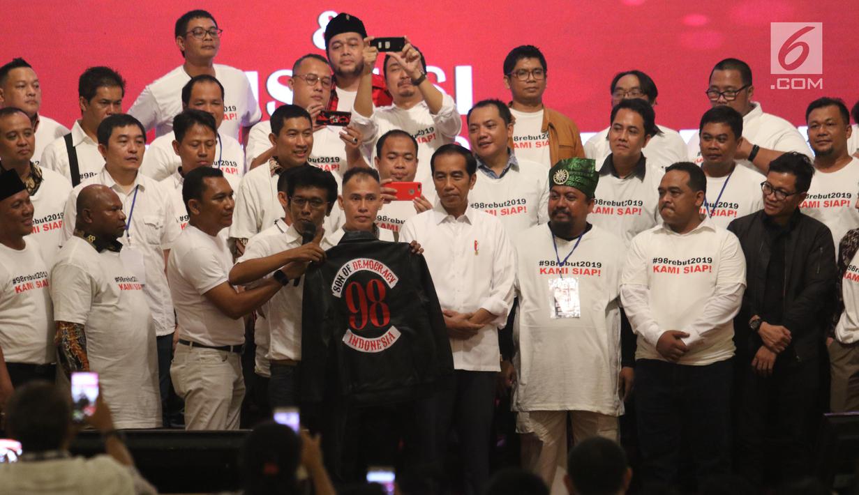 Aktivis 98 Adian Napitupulu memberikan jaket bertuliskan Son Of Democracy Indonesia 98 kepada Presiden Joko Widodo selama acara Halalbihalal bersama aktivis 98 di Jakarta, Minggu (16/6/2019). (Liputan6.com/Angga Yuniar)