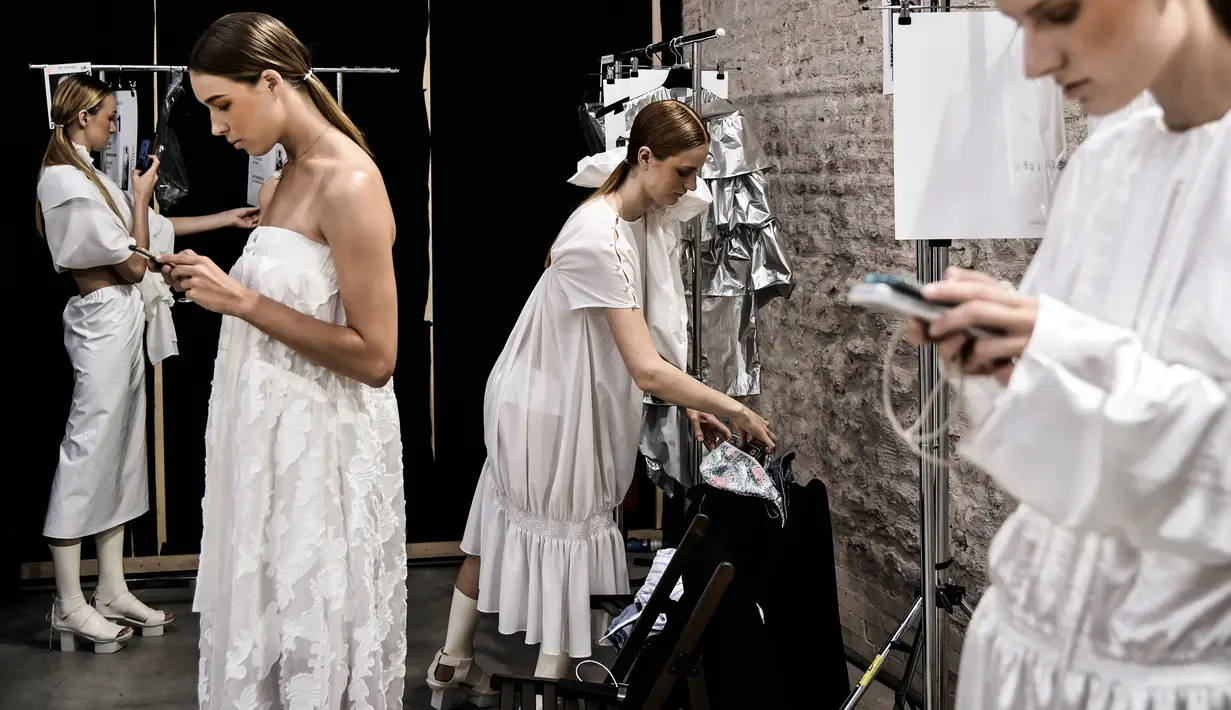 Sejumlah model bermain ponsel di belakang panggung sebelum tampil mengenakan busana Women Spring/Summer 2019 karya rumah mode Alberto Zambelli selama Milan Fashion Week di Italia (19/9). (AFP Photo/Marco Bertorello)