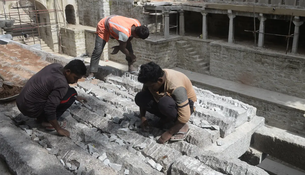 Buruh bekerja di sumur tangga Bansilalpet berusia abad ke-18, yang sedang menjalani pekerjaan restorasi, di Secunderabad, kota kembar Hyderabad, India (24/8/2022). (AFP/Noah Seelam)