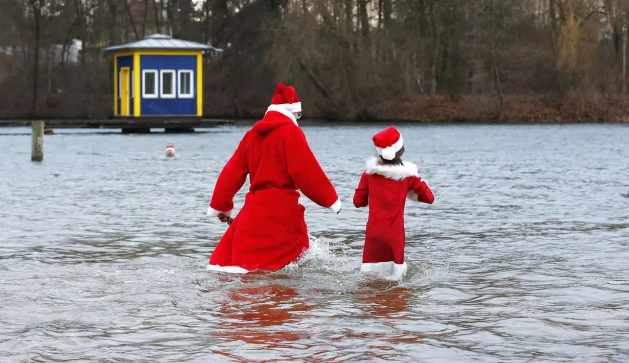 Puluhan anggota klub renang es "Berliner Seehunde" merayakan Natal dengan berenang di danau Orankesee, Berlin (25/12/2014). Dua anggota klub bersiap berenang di danau Orankesee, Berlin. (REUTERS/Fabrizio Bensch)