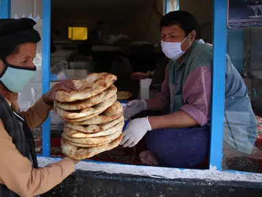 Seorang pria menerima roti gratis dari kota selama lockdownuntuk mencegah penyebaran virus corona, pada bulan puasa suci Ramadan di Kabul, Afghanistan, Senin, (4/5/2020). Muslim di seluruh dunia sedang melaksanakan Ramadan, ketika mereka menahan diri dari makan, minum dari subuh hingga senja. (AP/Ra