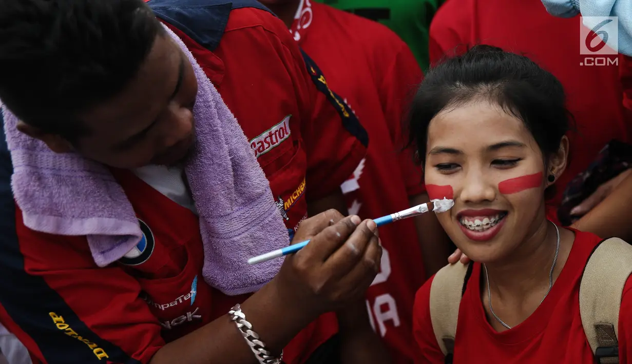 Seorang suporter wanita melukis pipinya dengan gambar bendera Merah Putih jelang semifinal SEA Games 2017 di Stadion Sham Alam Selangor, Malaysia, Sabtu (26/8). Timnas Indonesia U-22 bakal berlaga melawan Malaysia. (Liputan6.com/Faizal Fanani)