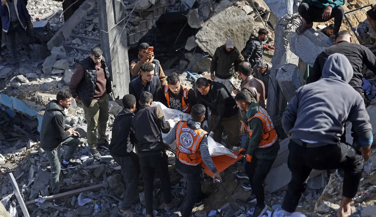 Untuk diketahui, hingga awal Februari 2026, berdasarkan data kementerian kesehatan di Gaza, jumlah total korban tewas mencapai 71.769 orang yang mayoritas wanita dan anak-anak. Sementara, ada lebih dari 171.483 orang mengalami luka-luka. Tampak dalam foto, para penyelamat membawa jenazah seorang korban di tengah reruntuhan kantor polisi Sheikh Radwan di Kota Gaza pada 31 Januari 2026. (Omar AL-QATTAA/AFP)