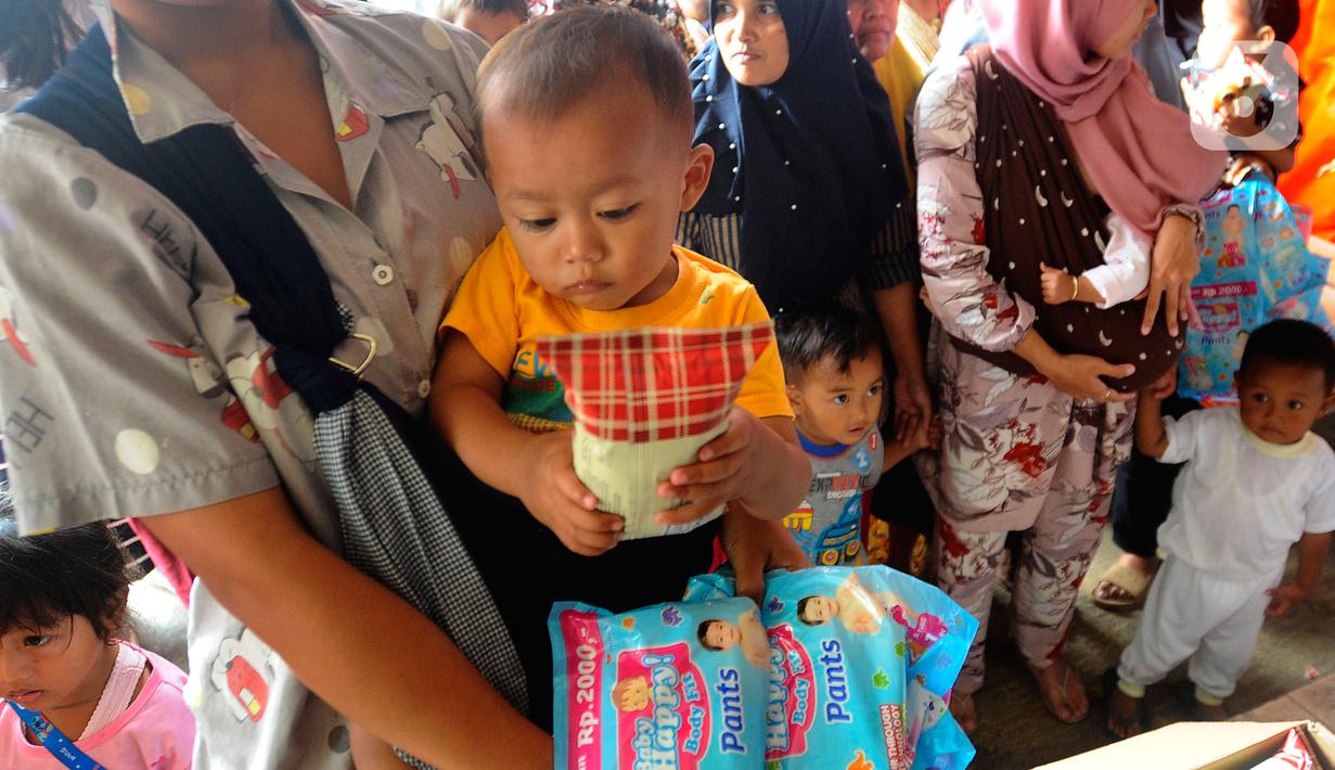 Warga antre mendapatkan pampers dan biskuit bagi anak-anak di Posko pengungsian Mangunkerta, Cianjur, Jumat (23/12/2022). Lebih dari sebulan sejak musibah gempa bumi 5,2 SR sejumlah warga masih tinggal di pengungsian dengan bantuan kebutuhan hidup dari para donatur. (merdeka.com/Arie Basuki)