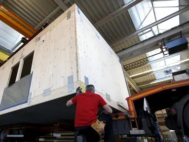 Pegawai bangunan saat merekonstruksi sebuah rumah prefabrikasi untuk pengungsi di perusahaan konstruksi Bauer Holzsysteme, Jerman, (7/12).  Rumah prefabrikasi ini dapat diangkut dan dipindahkan dengan menggunakan truk angkut. (REUTERS/Michaela Rehle)