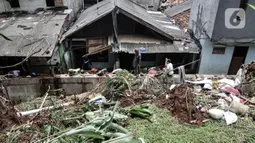 Warga membersihkan puing reruntuhan bangunan pascatanah longsor di kawasan Kemang Timur XI, Jakarta Selatan, Minggu (21/2/2021). Longsor terjadi akibat derasnya arus kali yang kemudian bangunan menimpa permukiman warga di bawahnya. (merdeka.com/Iqbal S. Nugroho)