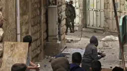 Tentara Israel berlindung sementara pengunjuk rasa Palestina bersiap untuk melempar batu saat bentrokan di pusat Kota Hebron, Tepi Barat, 4 Maret 2022. (HAZEM BADER/AFP)
