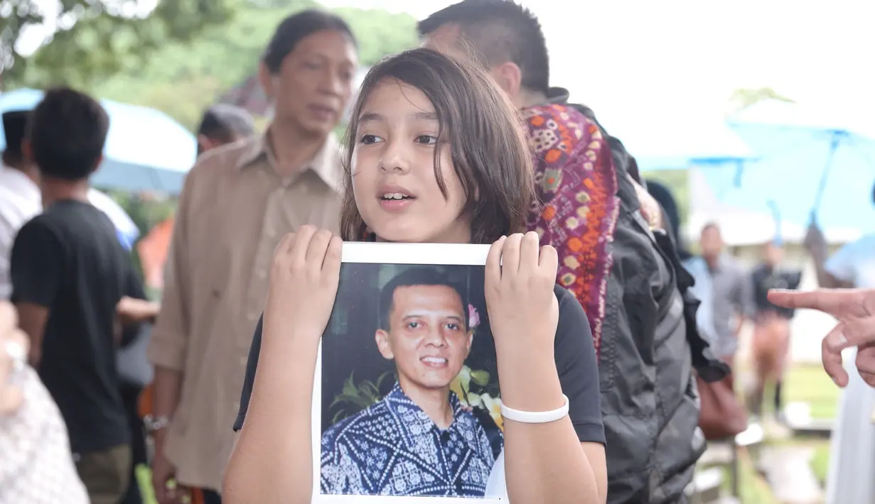 Begitu juga dengan sang anak semata wayangnya, Rajasa Satria Tama. Dari pengamatan, ia ikut terjun ke liang lahat membantu pemakaman ayahnya. Ia juga mengadzankan sebelum jenazah di uruk dengan tanah. (Galih W. Satria/Bintang.com)