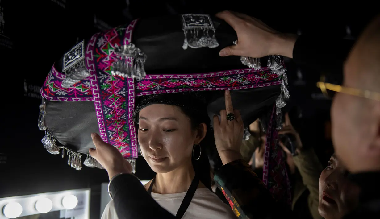 Seorang model saat dipakaikan topi di belakang panggung sebelum memamerkan koleksi oleh Zhang Kejia selama China Fashion Week di Beijing (26/3). (AFP Photo/Nicolas Asfouri)