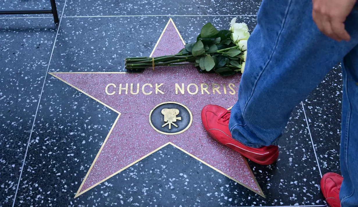 Pria yang terkenal dengan aneka film laga fenomenal ini meninggal dunia pada usia 86 tahun. Tampak dalam foto, seseorang berjalan di atas bintang Hollywood Walk of Fame Chuck Norris, menyusul berita kematiannya pada Jumat 20 Maret 2026, di Hollywood, California. (Frederic J. Brown/AFP)