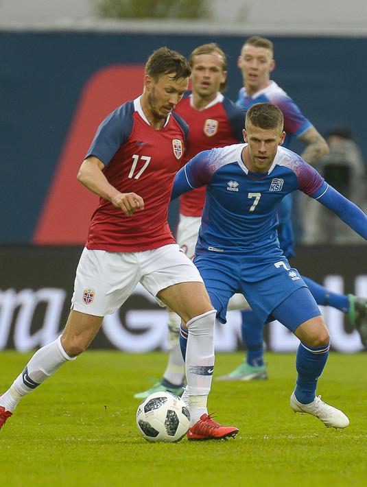Pemain Islandia, Johann Berg Gudmundsson (kanan) menutup pergerakan pemain Norwegia, Martin Linnes pada laga uji coba di Reykjavik, Islandia, (2/6/2018). Islandia kalah dari Norwegia 2-3. (AFP/Haraldur Gudjonsson)