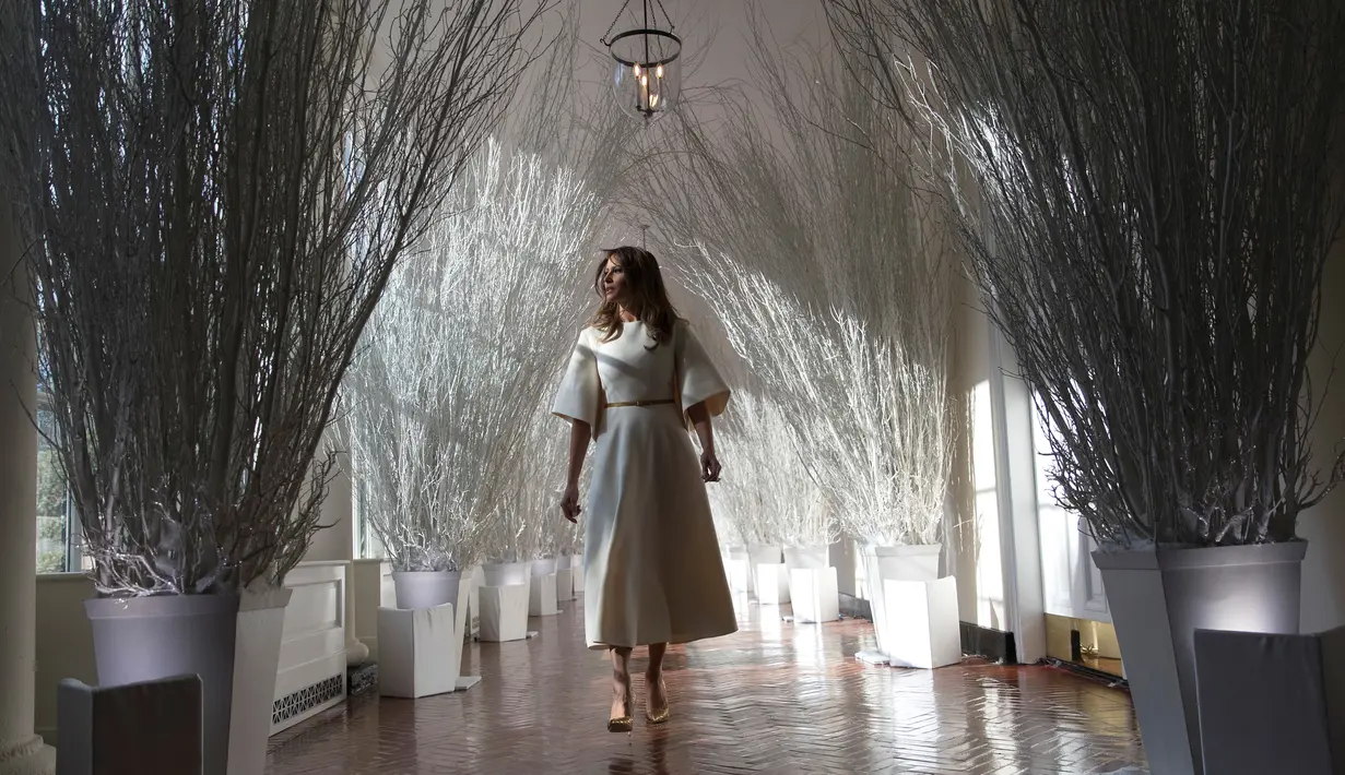 Ibu Negara Amerika Serikat (AS), Melania Trump berjalan di sepanjang lorong East Colonnade yang didekorasi untuk perayaan Natal dengan tema "Time-Honored Traditions" di Gedung Putih, Washington DC, Senin (27/11). (AP Photo/Carolyn Kaster)