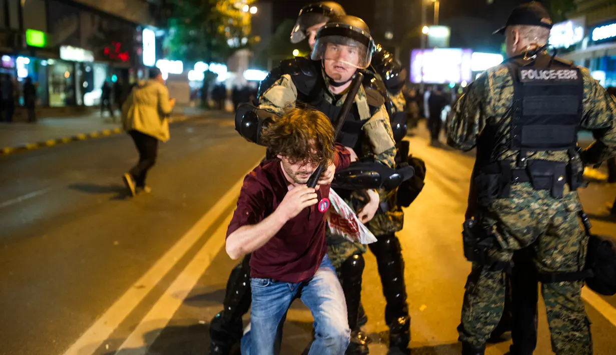 Polisi mengamankan pengunjuk rasa saat aksi menuntut pengunduran diri Presiden Gjorge Ivanov di ibu kota Makedonia, Skopje, Rabu (13/4). Ribuan demonstran memprotes keputusan Presiden memberikan pengampunan bagi 56 politikus (Robert ATANASOVSKI/AFP)