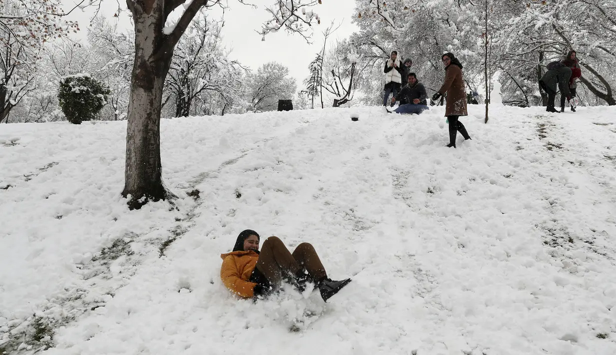 Seorang wanita meluncur di salju di sebuah taman di Teheran utara, Iran (19/1/2020). Salju tebal menutupi jalan-jalan Teheran, menyebabkan penundaan penerbangan dan munutup sekolah, kata pihak berwenang di ibukota Iran. (AP Photo / Vahid Salemi)