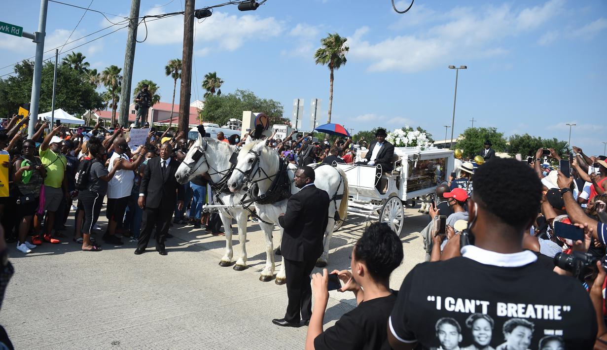 Orang-orang menyaksikan kereta kuda membawa jenazah George Floyd menuju pemakaman Houston Memorial Gardens di Houston, Texas, Amerika Serikat, Selasa (9/6/2020). Floyd akan dimakamkan di samping makam ibunya, Larcenia Floyd. (Andrew CABALLERO-REYNOLDS/AFP)
