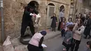 Seorang pria Yahudi ultraortodoks mengayunkan seekor ayam di atas kepala anggota keluarganya saat melakukan ritual Kapparot di Yerusalem, 13 September 2021. Kapparot adalah ritual transfer dosa ke ayam yang dilakukan sebelum Yom Kippur (Hari Penebusan). (MENAHEM KAHANA/AFP)