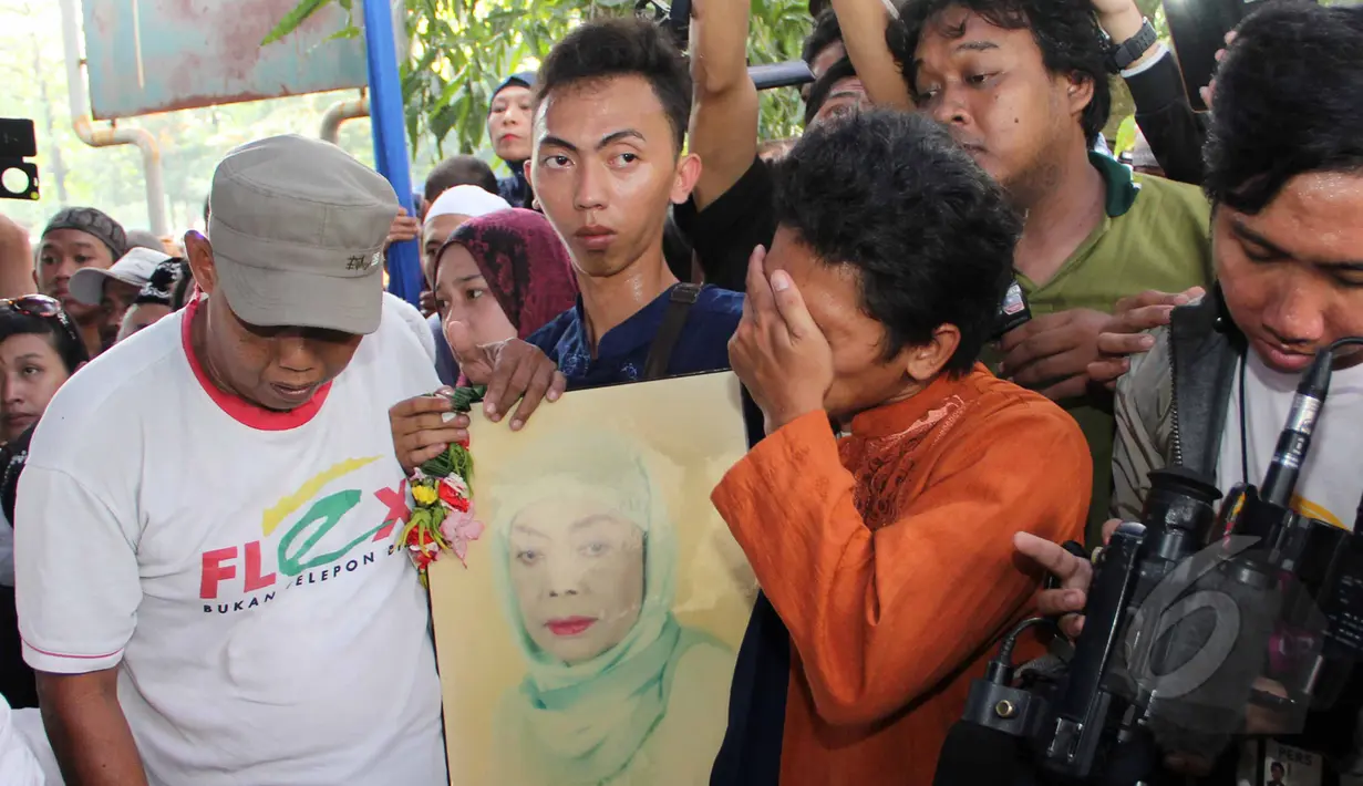 Salah satu kerabat menangis sambil memegang foto semasa hidup komedian Betawi Nur Sarinuri atau lebih dikenal Mpok Nori seusai dimakamkan di TPU Pondok Ranggon, Jakarta Timur, Jumat (3/4/2015). (Liputan6.com/Helmi Afandi)