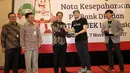 Direktur Bisnis Bank DKI,  Antonius Widodo Mulyono (tengah) dan CMO Go-Jek, Piotr Jakubowski (kedua kanan) tukar cinderamata usai penandatanganan kerjasama interoperabilitas uang elektronik dan perluasan channel pembayaran pajak. (Liputan6.com/Pool/Budi)