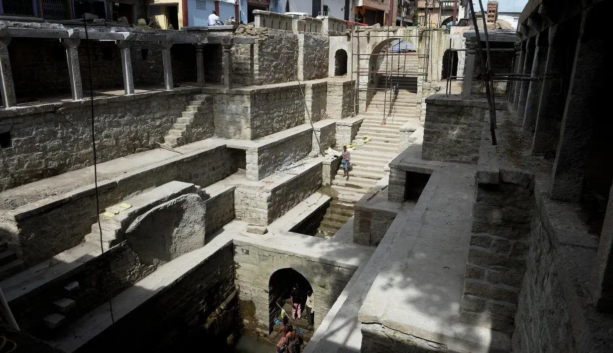 Orang-orang mandi di sumur tangga Bansilalpet berusia abad ke-18 yang sedang menjalani pekerjaan restorasi di Secunderabad, kota kembar Hyderabad, India (24/8/2022). (AFP/Noah Seelam)