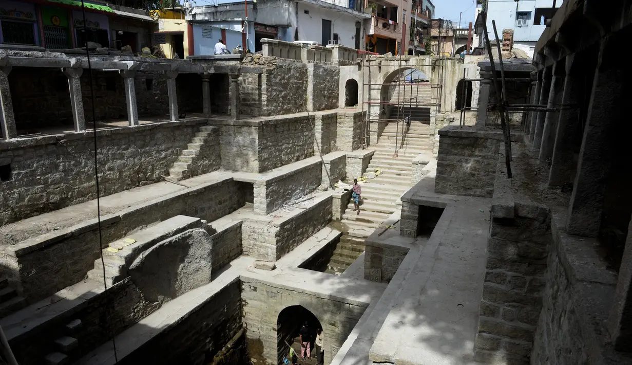 Orang-orang mandi di sumur tangga Bansilalpet berusia abad ke-18 yang sedang menjalani pekerjaan restorasi di Secunderabad, kota kembar Hyderabad, India (24/8/2022). (AFP/Noah Seelam)