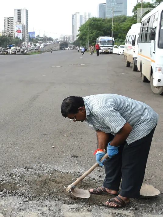 Foto pada 29 Agustus 2018, Dadarao Bilhore menutup jalan berlubang di jalan raya Western Express, Mumbai di India. Pria yang dijuluki "Ayah lubang jalanan" itu menutup hampir 600 lubang di jalanan Mumbai selama tiga tahun terakhir (INDRANIL MUKHERJEE/AFP)