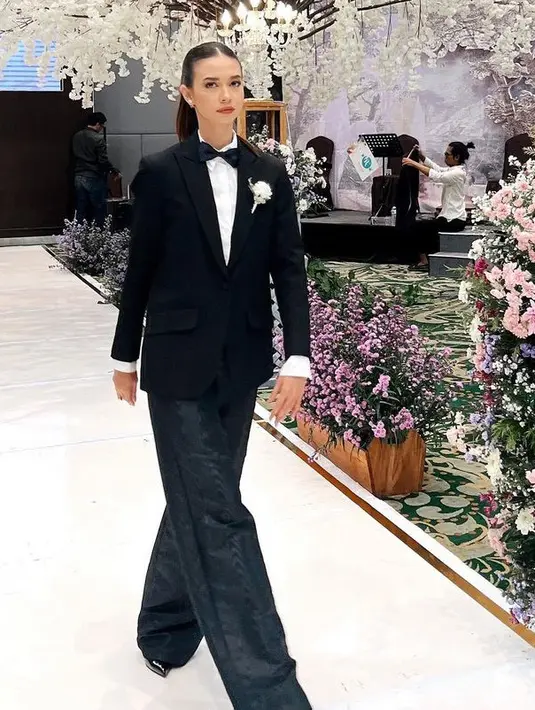Tak hanya tampil feminim saat jadi bridesmaid, Yuki juga tampil bois mengenakan jas hitam serasi dengan celana panjangnya. Ia pun memadukannya dengan inner kemeja putih dan dasi kupu-kupu serta bros bunga putihnya. Ia pun mengenakan heels hitam. [@yukikt]