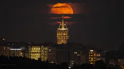 Bulan purnama muncul di belakang Menara Galata, Istanbul, Turki, 14 Juni 2022. Fenomena ini disebut juga sebagai Strawberry Supermoon karena terjadi pada saat panen strawberry. (AP Photo/Emrah Gurel)