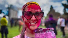 Seorang wanita yang mengenakan kacamata hitam memoles wajahnya dengan bedak warna-warni saat merayakan Holi, festival warna Hindu, di bagian Encino, Los Angeles, Minggu, 24 Maret 2024. (AP Photo/Richard Vogel)