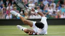 Petenis Serbia, Novak Djokovic jatuh tersungkur ketika menghadapi petenis AS, Denis Kudla pada babak kedua Wimbledon di All England Lawn Tennis Club, London, Kamis (4/7/2019) dini hari. Djokovic melangkah ke babak ketiga setelah menang dengan skor 6-3 6-2 6-2. (AP Photo/Tim Ireland)