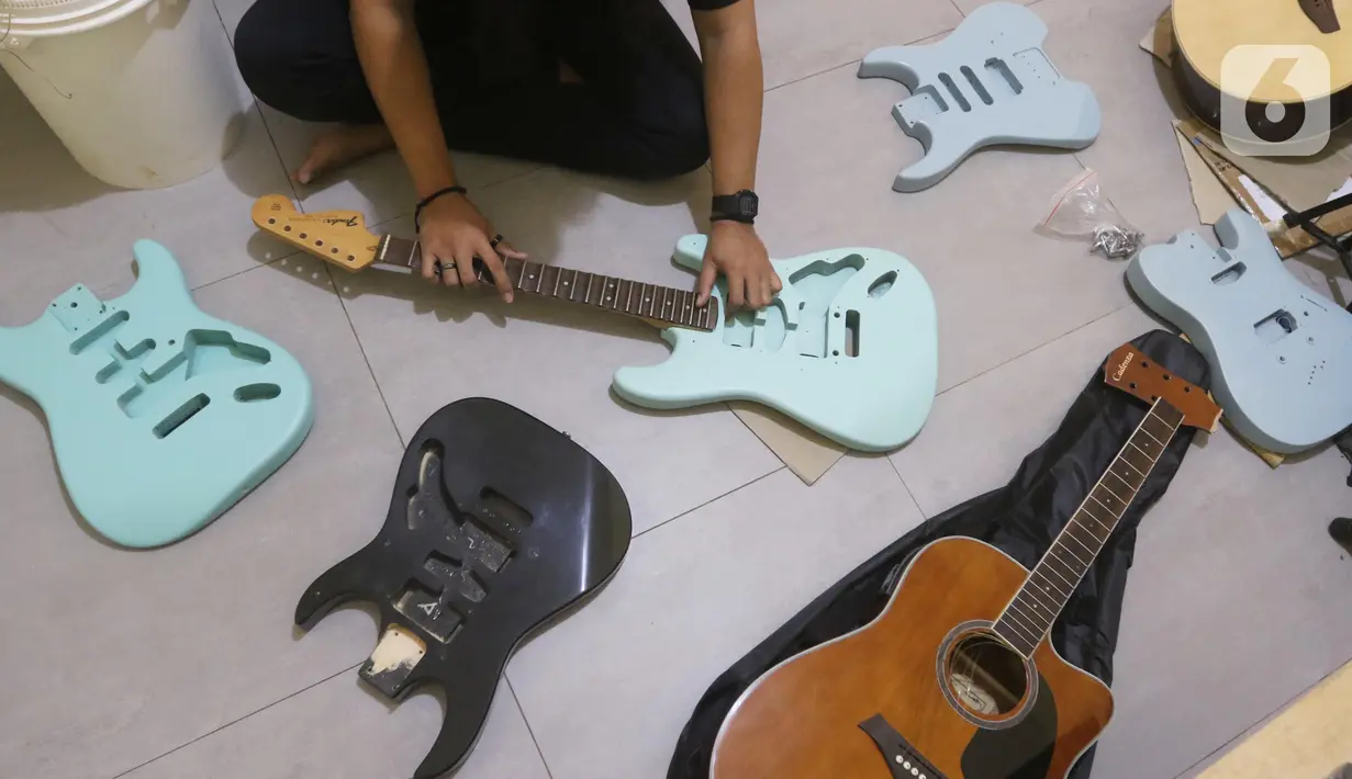 Pemilik showroom dan bengkel Gitar "music666", Ridwan dan Rudi mendemonstrasikan gitar yang akan dijual secara daring di Ciledug, Tangerang, Rabu (22/7/2020). Pemerintah menargetkan 10 juta usaha mikro kecil menengah (UMKM) pada tahun ini terhubung dengan platform digital (Liputan6.com/Angga Yuniar)