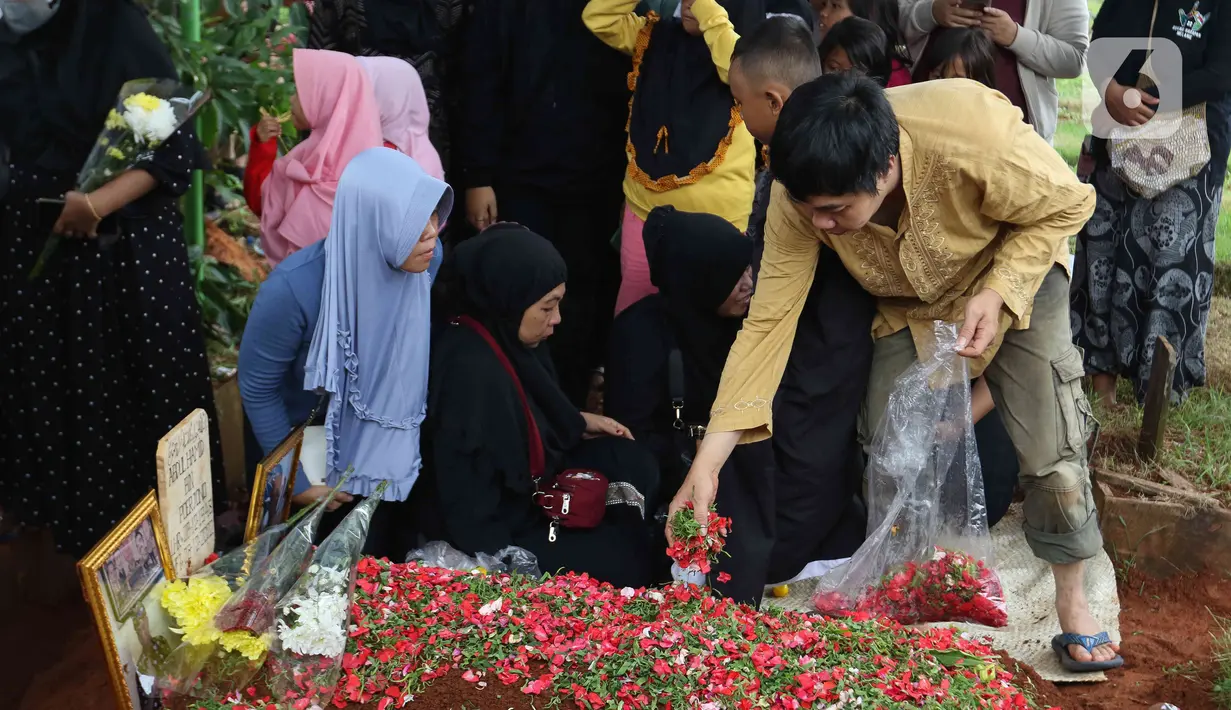 Seorang kerabat menabur bunga saat pemakaman Abdul Hamid alias Pak Ogah di TPU (Tempat Pemakaman Umum) Jatisari, Bekasi, Jawa Barat, Kamis (29/12/2022). Pak Ogah salah satu pengisi suara dalam serial film Si Unyil meninggal pada (28/12/2022) di usia 74 tahun. (Liputan6.com/Herman Zakharia)