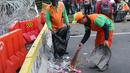 Petugas PPSU membersihkan sampah sisa perayaan Hari Buruh Internasional di kawasan Silang Barat Daya Monas, Jakarta, Rabu (1/5). Buruh dari sejumlah perkumpulan merayakan Hari Buruh Internasional dengan aksi damai. (Liputan6.com/Helmi Fithriansyah)