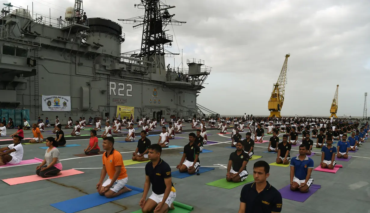 Sejumlah Personel Angkatan Laut India saat mengikuti yoga bersama menandai Hari Yoga Internasional di atas kapal induk INS Viraat di pelabuhan Mumbai, India, (21/6). Olahraga yoga telah menyatukan dunia dengan India. (AFP Photo/Punit Paranjpe)