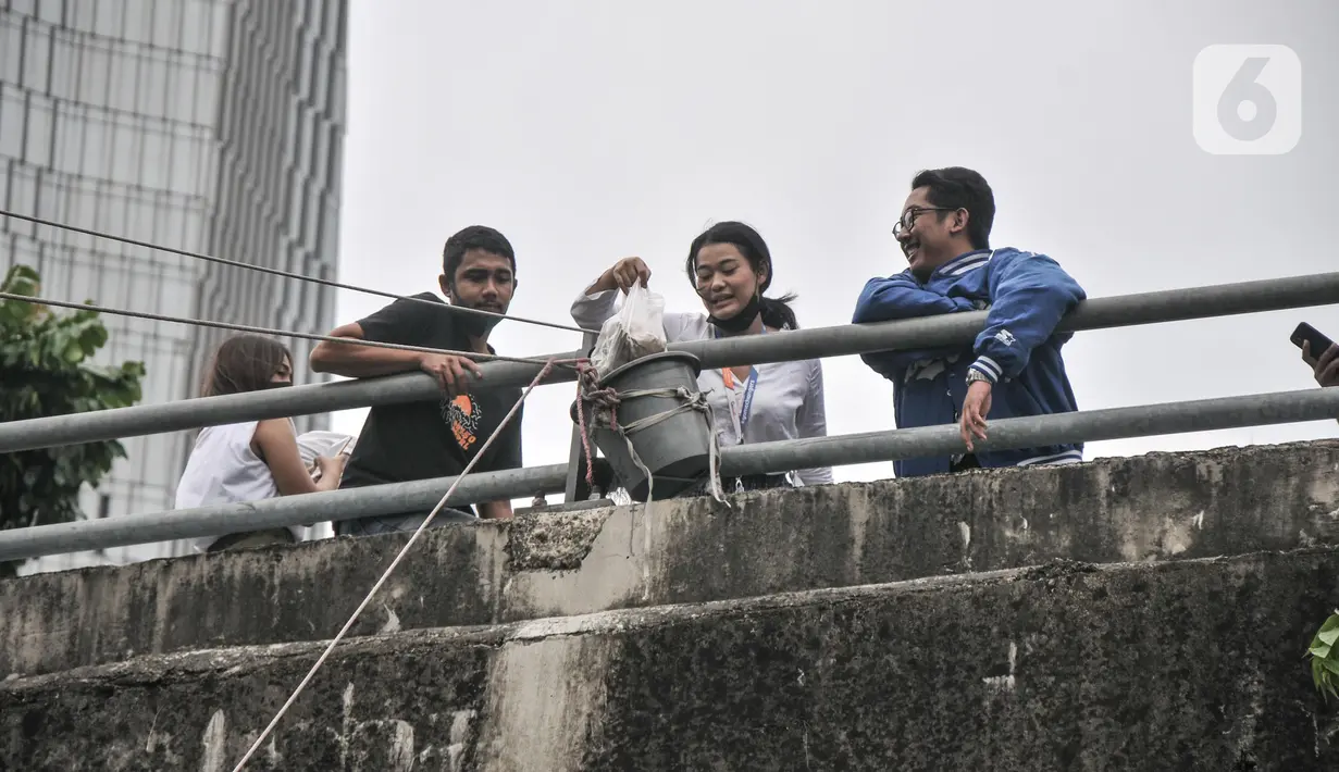 Pembeli saat mengambil makanan yang dibeli di warung kerek di Kuningan Barat, Mampang Prapatan, Jakarta Selatan, Rabu (25/5/2022). Setelah sempat terpuruk akibat pandemi Covid-19, warung kerek yang berada di tepi Kali Mampang ini kembali menggeliat. Agus (42), salah satu pedagang mengungkapkan akibat pandemi penjualan makanan di warung kerek merosot hingga 70 persen. (merdeka.com/Iqbal S Nugroho)