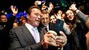 Aktor yang juga mantan Gubernur California, Arnold Schwarzenegger berswafoto dengan Presiden Prancis, Emmanuel Macron (tengah) berlatar belakang Menara Eiffel seusai menghadiri KTT One Planet Summit di Paris, Selasa (12/12). (AP/Thibault Camus, Pool)