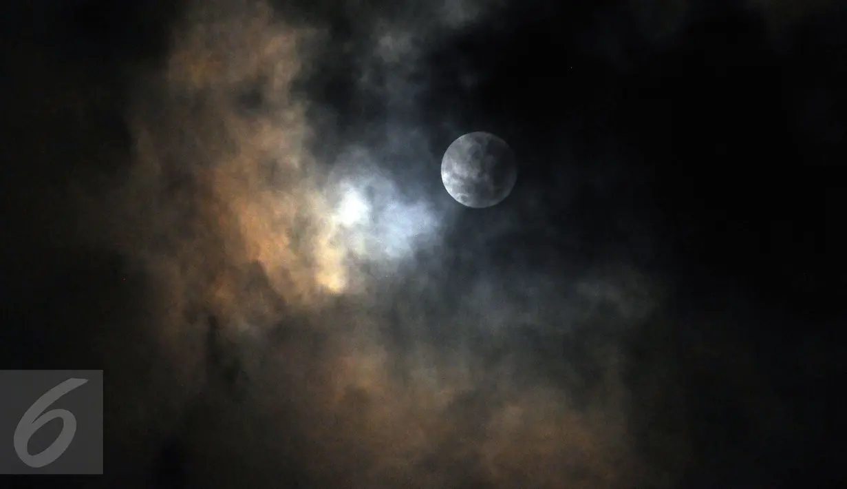 Fenomena alam Supermoon mulai tertutup awan tampak di langit Kabupaten Bogor, Jawa Barat, Senin (14/11). Fenomena ini terjadi saat bulan mencapai titik terdekat dengan bumi dalam kondisi purnama atau penuh. (Liputan6.com/Helmi Fithriansyah)